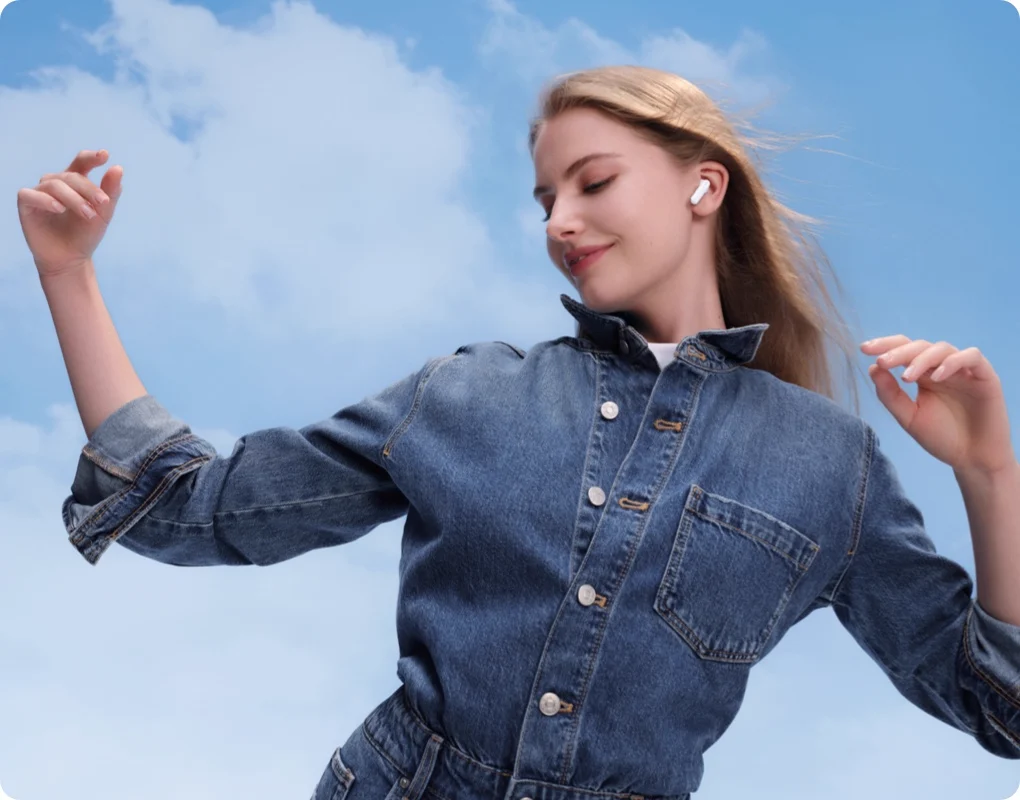 A woman wearing the earbuds against the sky